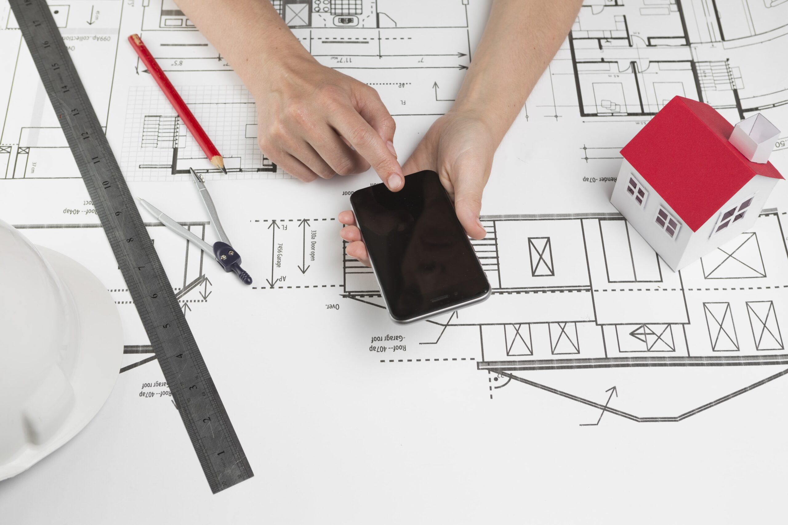 human-hand-using-cellphone-blueprint-workplace-min